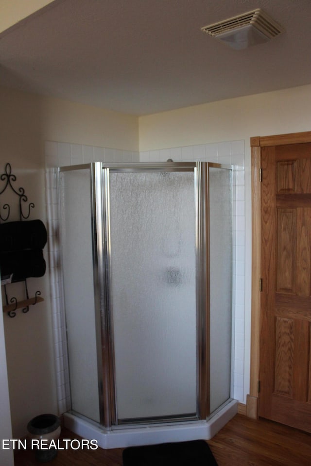 bathroom with an enclosed shower and hardwood / wood-style flooring