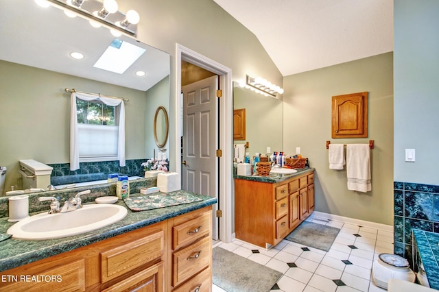 bathroom with vanity, tile patterned floors, and lofted ceiling with skylight