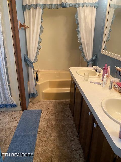 bathroom with dual sinks, large vanity, and a bath to relax in