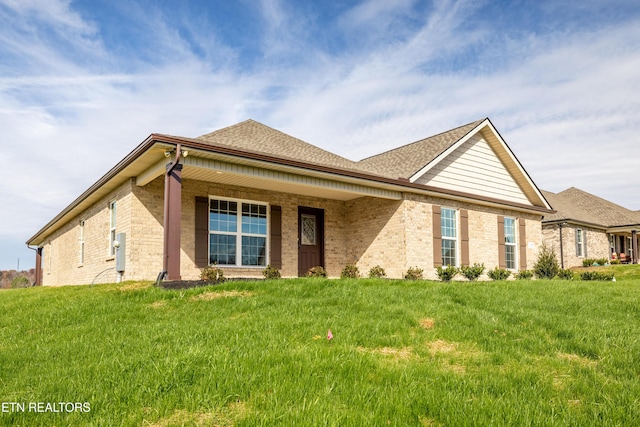 view of front of house with brick siding, roof with shingles, and a front lawn