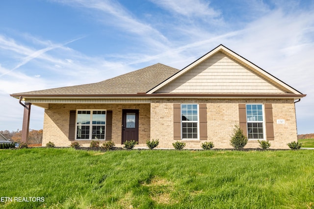 view of front of home featuring brick siding, a shingled roof, and a front lawn