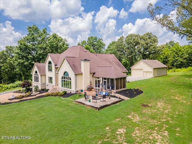 rear view of house with a sunroom, a lawn, and a garage