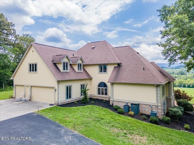 view of front of property with a front yard, central AC, and a garage