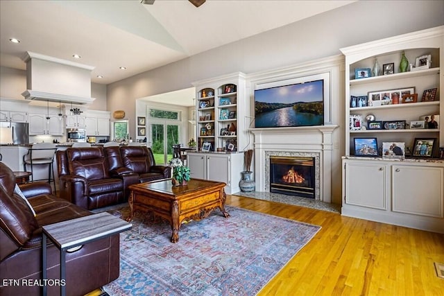 living room featuring lofted ceiling, light wood-type flooring, and a premium fireplace