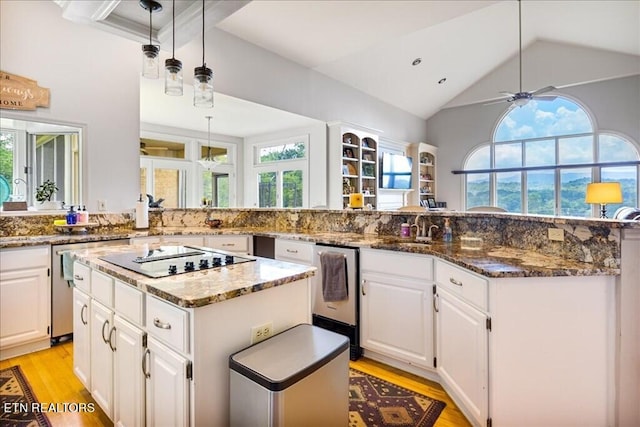 kitchen featuring hanging light fixtures, a kitchen island, ceiling fan, dark stone countertops, and white cabinetry