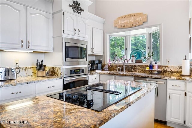 kitchen with appliances with stainless steel finishes, sink, light stone counters, and white cabinets