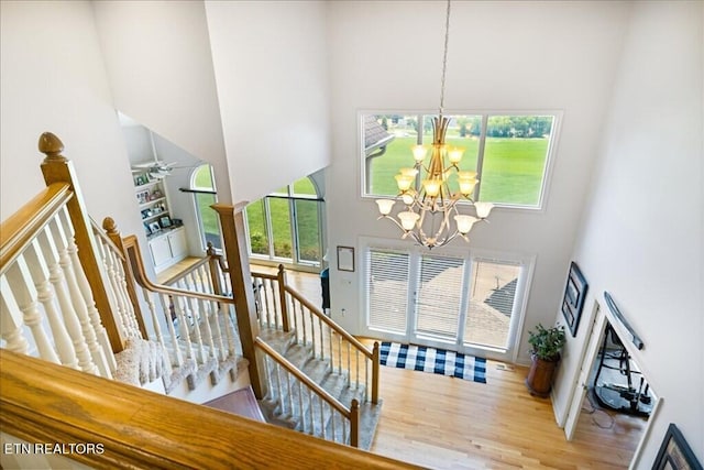 entrance foyer with a towering ceiling, light wood-type flooring, and ceiling fan with notable chandelier