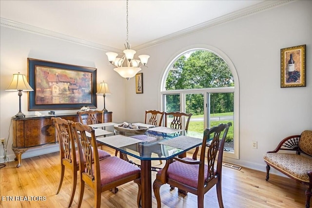 dining space with light hardwood / wood-style flooring, a notable chandelier, and crown molding