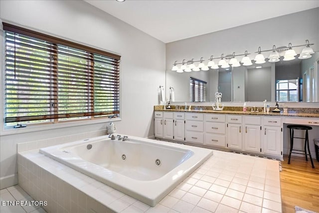 bathroom featuring double sink, a relaxing tiled bath, hardwood / wood-style floors, and vanity with extensive cabinet space