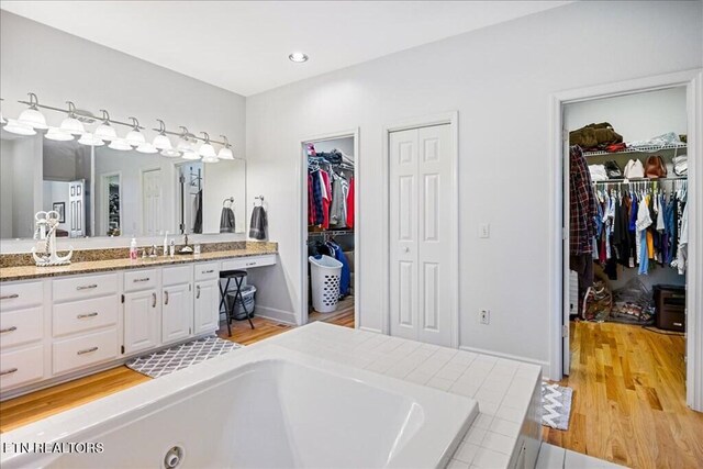 bathroom featuring double vanity, a bathtub, and hardwood / wood-style flooring