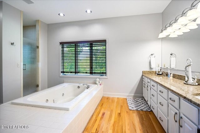 bathroom with independent shower and bath, double sink vanity, and hardwood / wood-style flooring