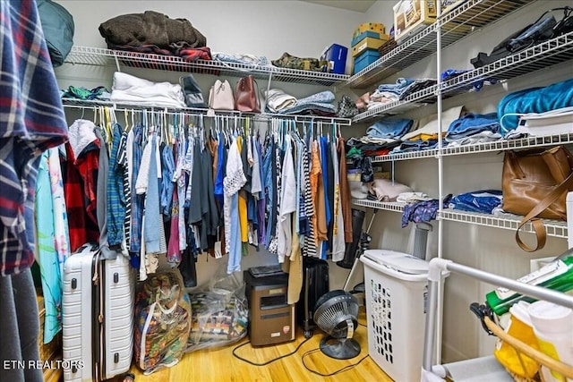 walk in closet with light hardwood / wood-style floors