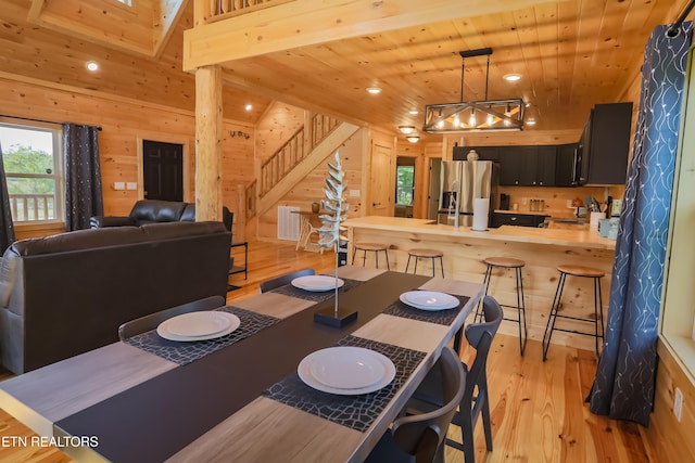 dining room with stairs, wooden walls, light wood-style flooring, and wood ceiling