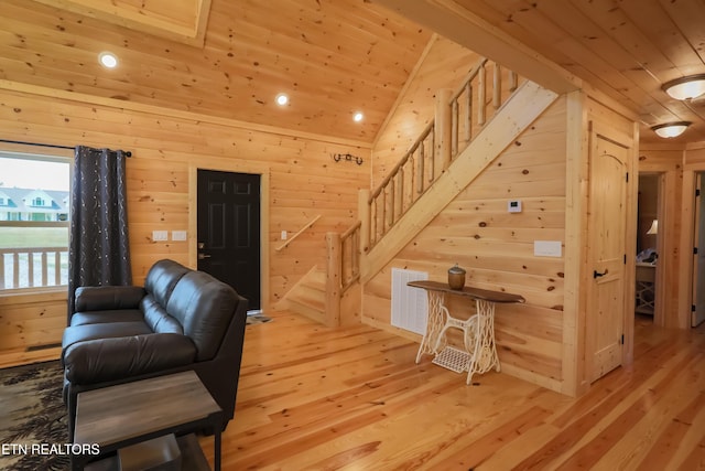 living room with wooden ceiling, wood walls, stairway, and light wood finished floors