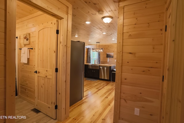 hall with recessed lighting, light wood-type flooring, wooden ceiling, wooden walls, and visible vents