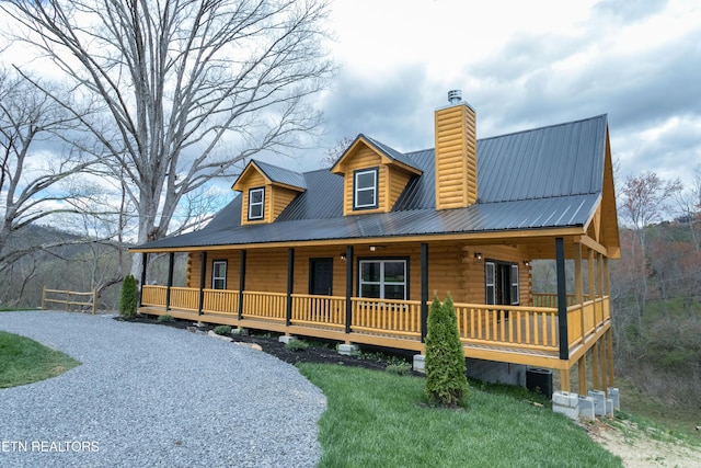 log cabin with a front yard, central air condition unit, a chimney, metal roof, and a porch