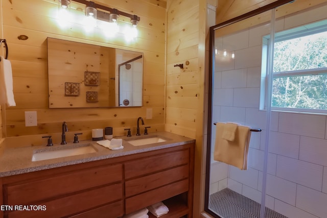 bathroom with a shower stall, double vanity, wooden walls, and a sink