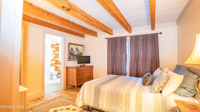 bedroom with beamed ceiling, ensuite bathroom, and hardwood / wood-style floors