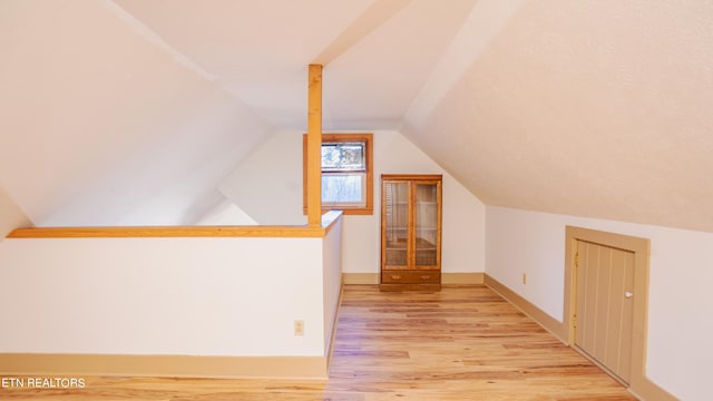 additional living space featuring light hardwood / wood-style floors and lofted ceiling