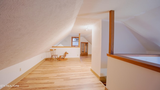 bonus room with light hardwood / wood-style flooring, a textured ceiling, and vaulted ceiling