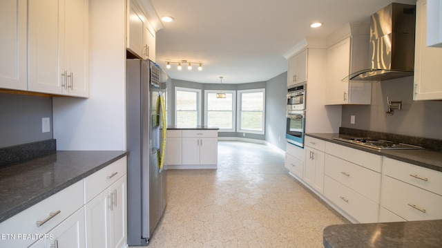 kitchen with white cabinetry, stainless steel appliances, rail lighting, wall chimney range hood, and pendant lighting