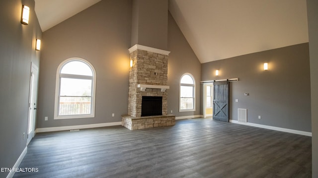 unfurnished living room with high vaulted ceiling, dark hardwood / wood-style floors, a fireplace, and a healthy amount of sunlight