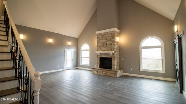 unfurnished living room featuring high vaulted ceiling, dark hardwood / wood-style flooring, a fireplace, and decorative columns