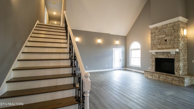 stairs with high vaulted ceiling, dark hardwood / wood-style flooring, and a fireplace