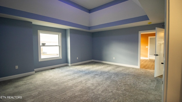 carpeted empty room featuring a raised ceiling