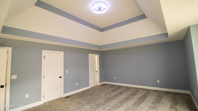 carpeted empty room with a tray ceiling