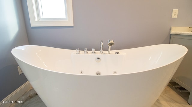 bathroom with a tub, tile floors, and vanity