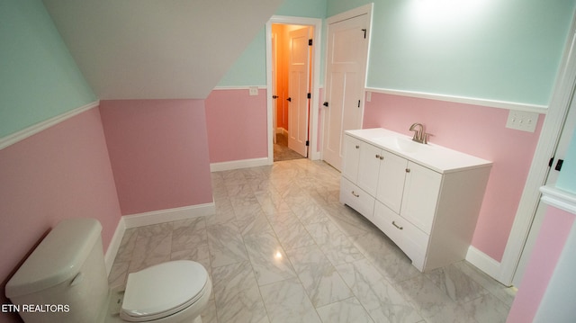 bathroom with lofted ceiling, toilet, tile flooring, and vanity