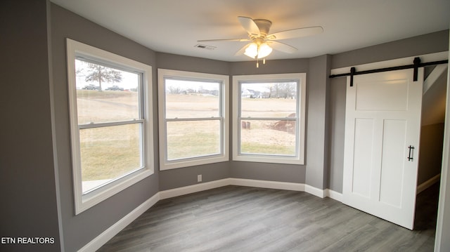 interior space featuring a barn door, light hardwood / wood-style floors, and ceiling fan