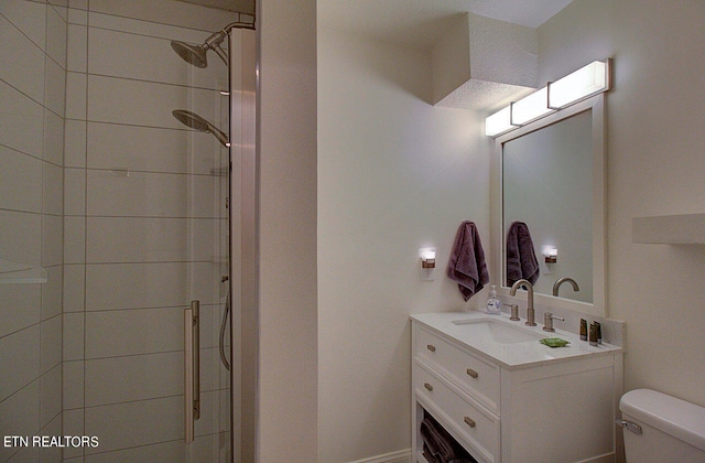 bathroom featuring toilet, a shower with shower door, and vanity