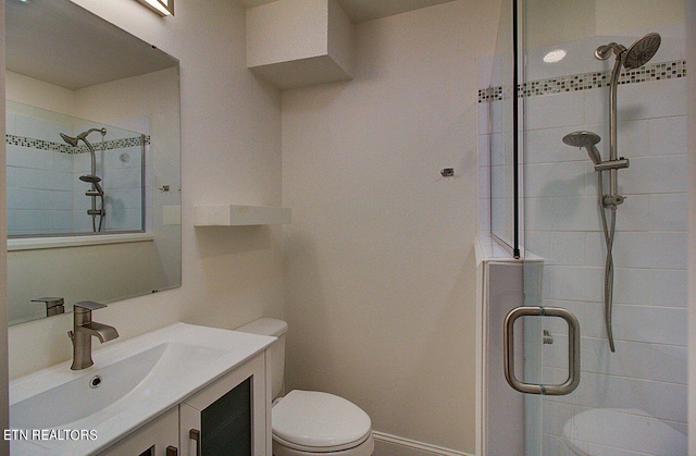 bathroom featuring toilet, a shower with door, and vanity