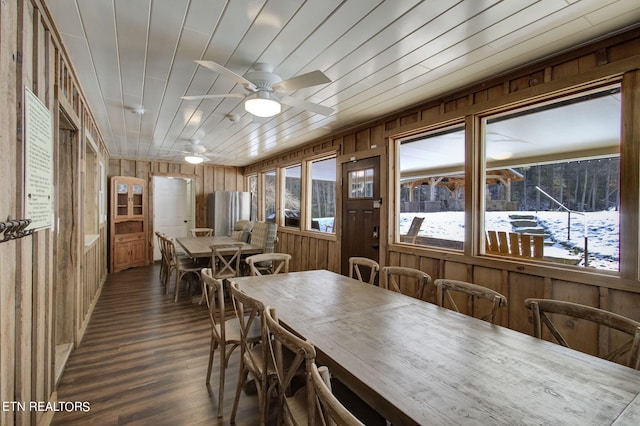 dining area with wooden walls, ceiling fan, and dark hardwood / wood-style flooring