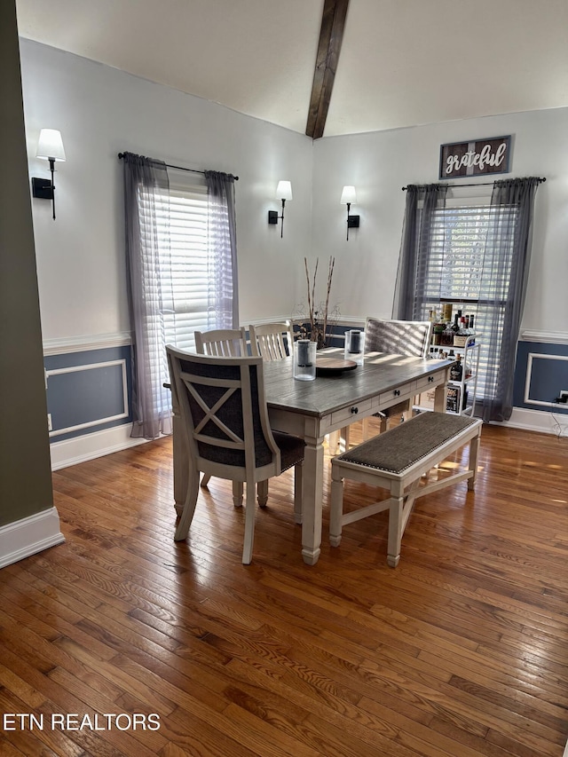 dining room featuring wood-type flooring, lofted ceiling with beams, and wainscoting