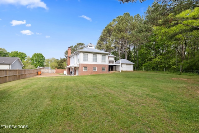 back of property with a chimney, fence, a garage, brick siding, and a yard