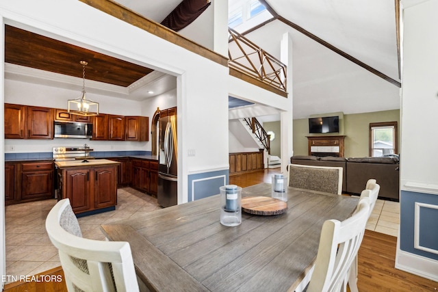 dining room with a high ceiling, stairway, a fireplace, and light tile patterned floors