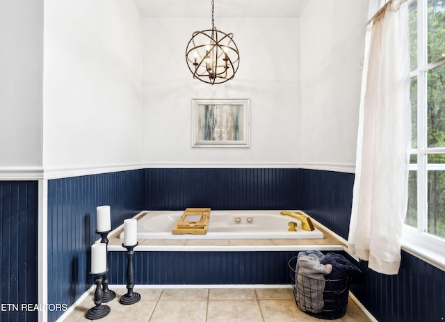 full bathroom featuring a bath, a wainscoted wall, tile patterned flooring, and a notable chandelier
