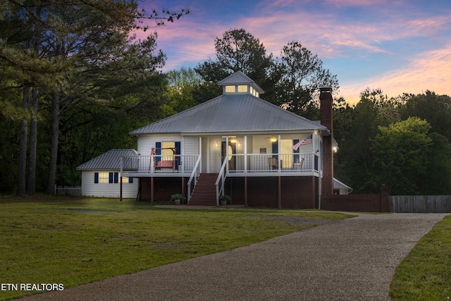 view of front of property featuring stairway, a chimney, fence, a porch, and a front yard