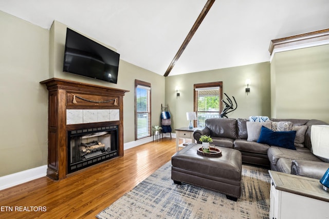 living area featuring baseboards, vaulted ceiling, wood finished floors, and a fireplace
