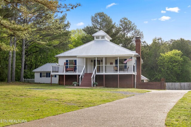 view of front of house featuring a front lawn, a chimney, covered porch, fence, and stairs