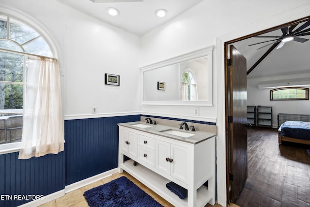bathroom with ensuite bath, a wainscoted wall, a sink, and double vanity