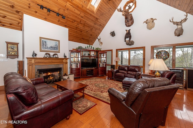 living room featuring a skylight, rail lighting, high vaulted ceiling, wood-type flooring, and wood ceiling