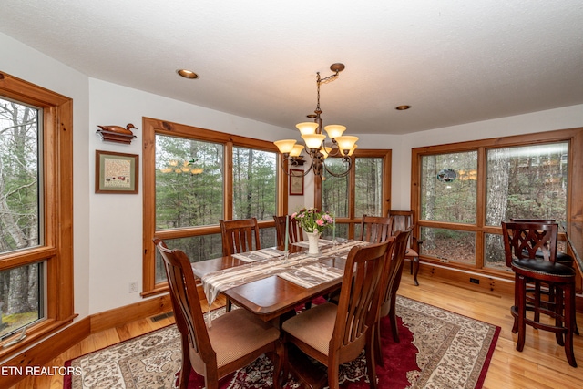 dining area with plenty of natural light, a notable chandelier, and light wood-type flooring