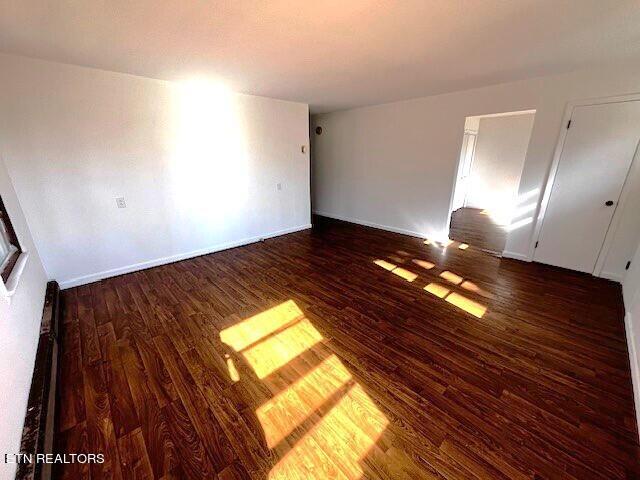 empty room with dark hardwood / wood-style flooring