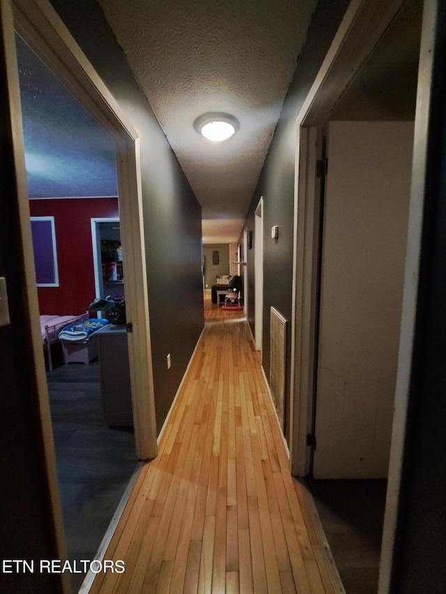 hallway featuring light hardwood / wood-style floors and a textured ceiling