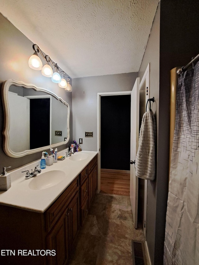 bathroom featuring double sink, tile flooring, a textured ceiling, and oversized vanity