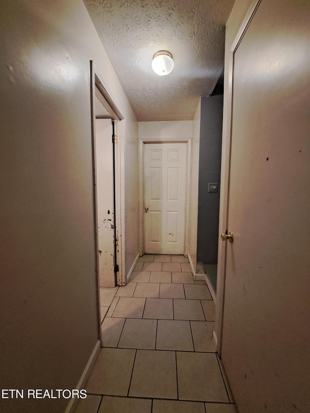 corridor featuring light tile floors and a textured ceiling